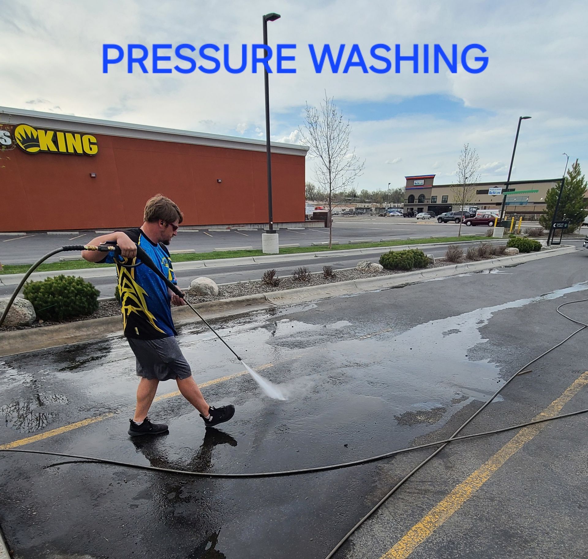 A man is using a pressure washer to clean a parking lot