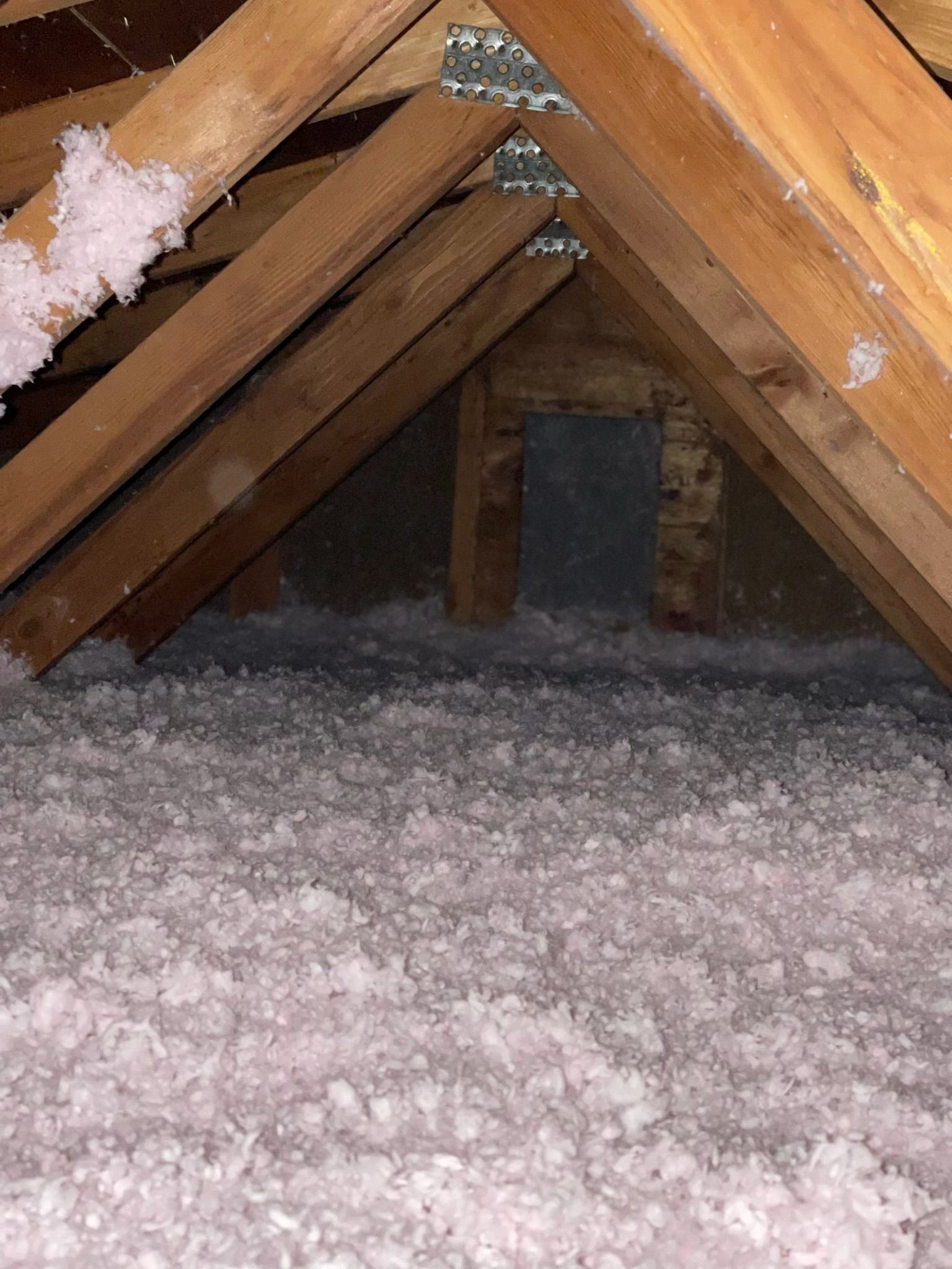 Attic with exposed wooden rafters and a floor covered in white insulation or snow-like material