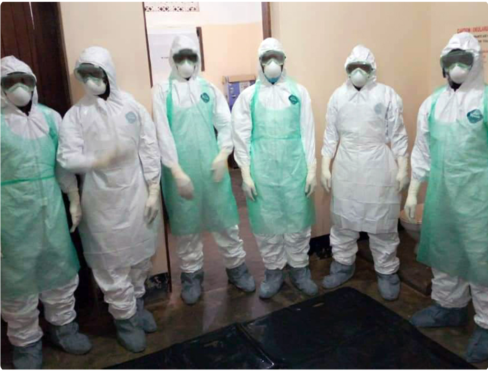 A group of people wearing protective suits and aprons are standing next to each other.