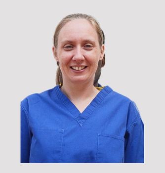 A woman in a blue scrub top is smiling for the camera