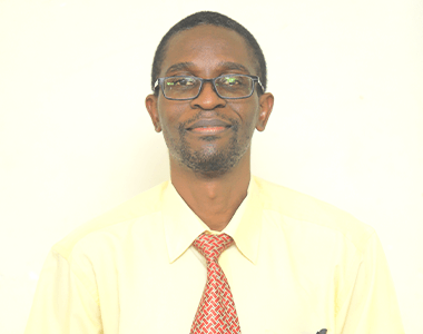 A man wearing glasses and a tie is smiling for the camera.