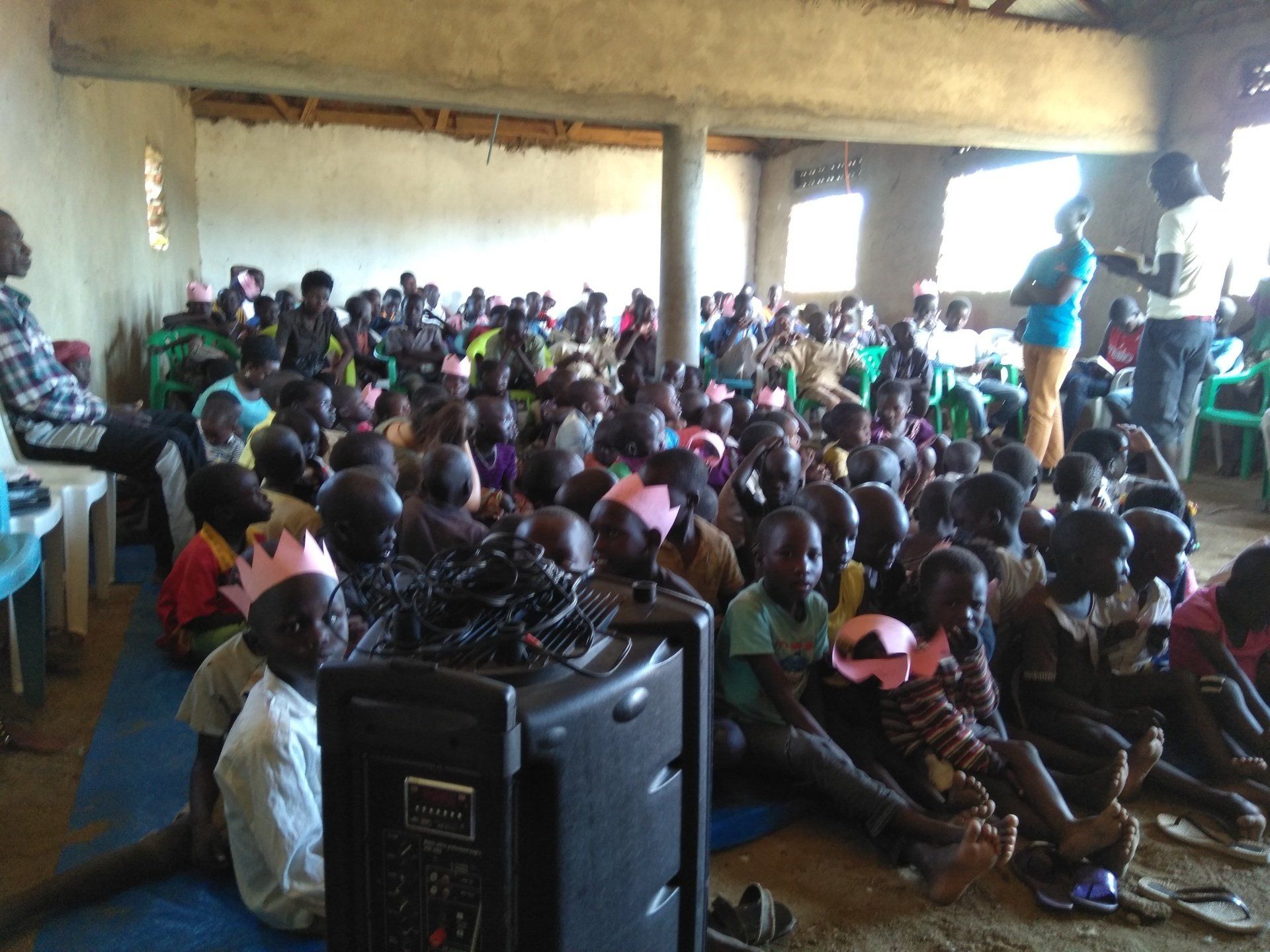 A large group of children are sitting on the floor in a room.