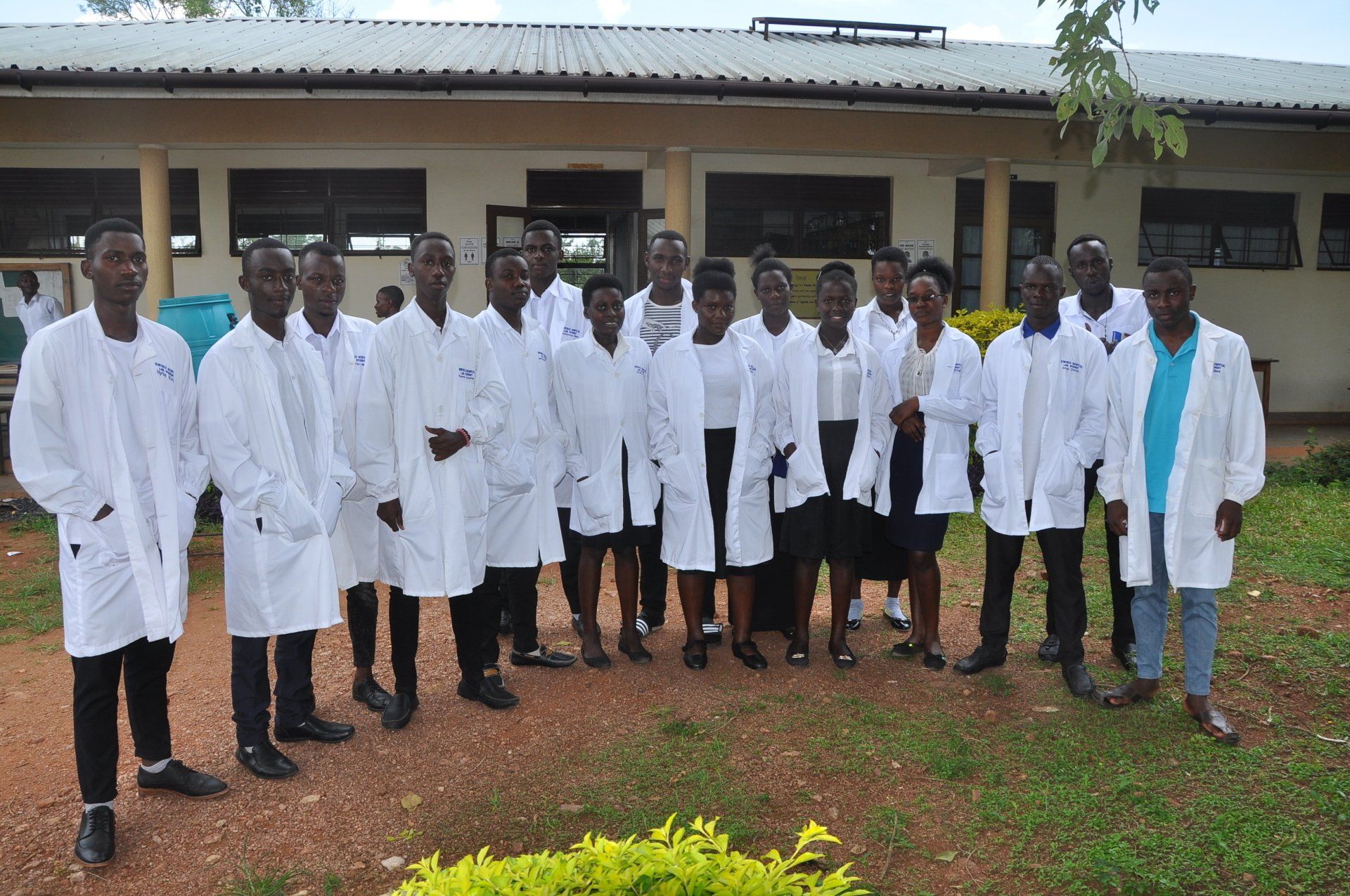 A group of people standing in front of a building wearing lab coats