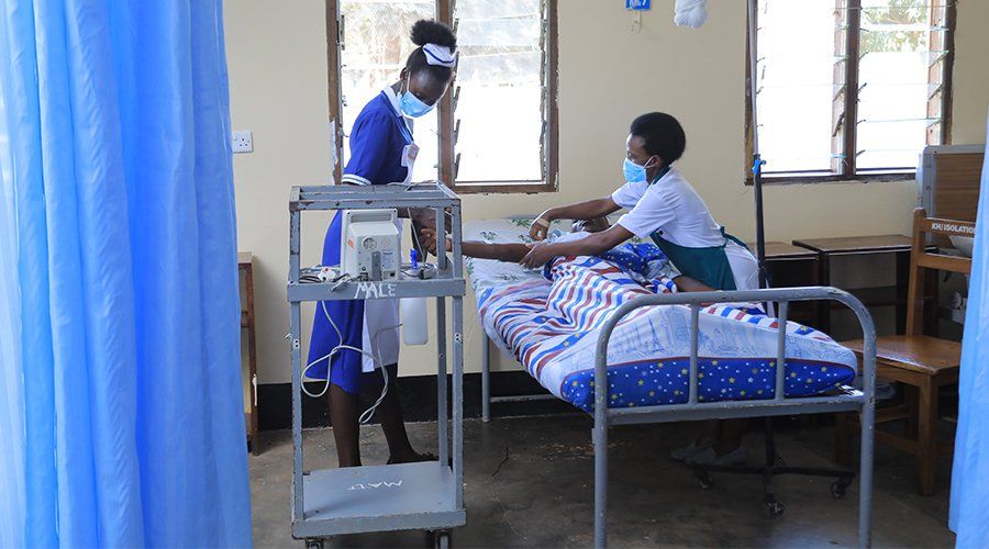 Two nurses are working on a patient in a hospital room