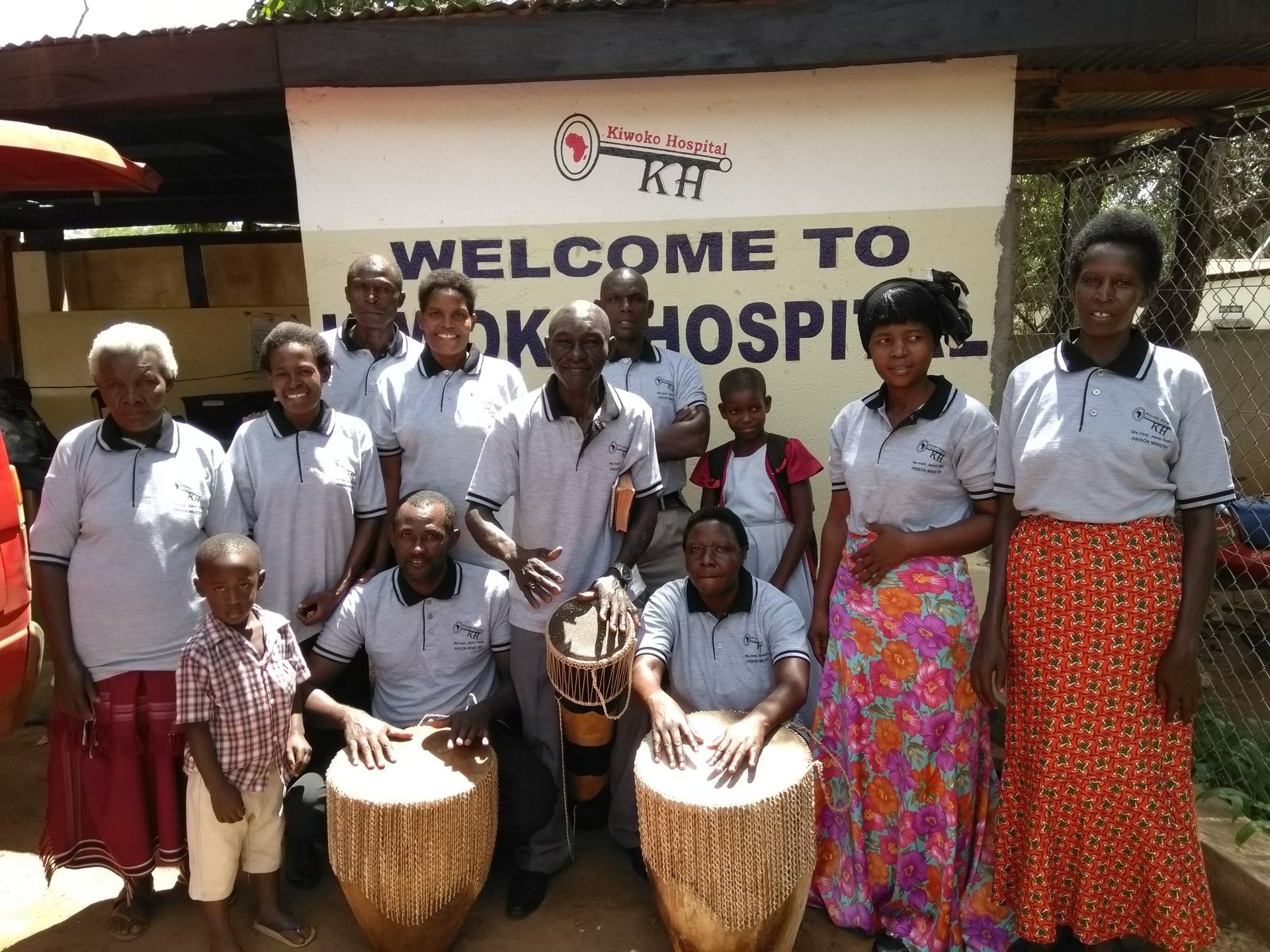 A group of people standing in front of a sign that says welcome to ok hospital