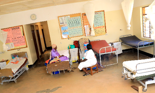 A hospital room with many beds and a clock on the wall