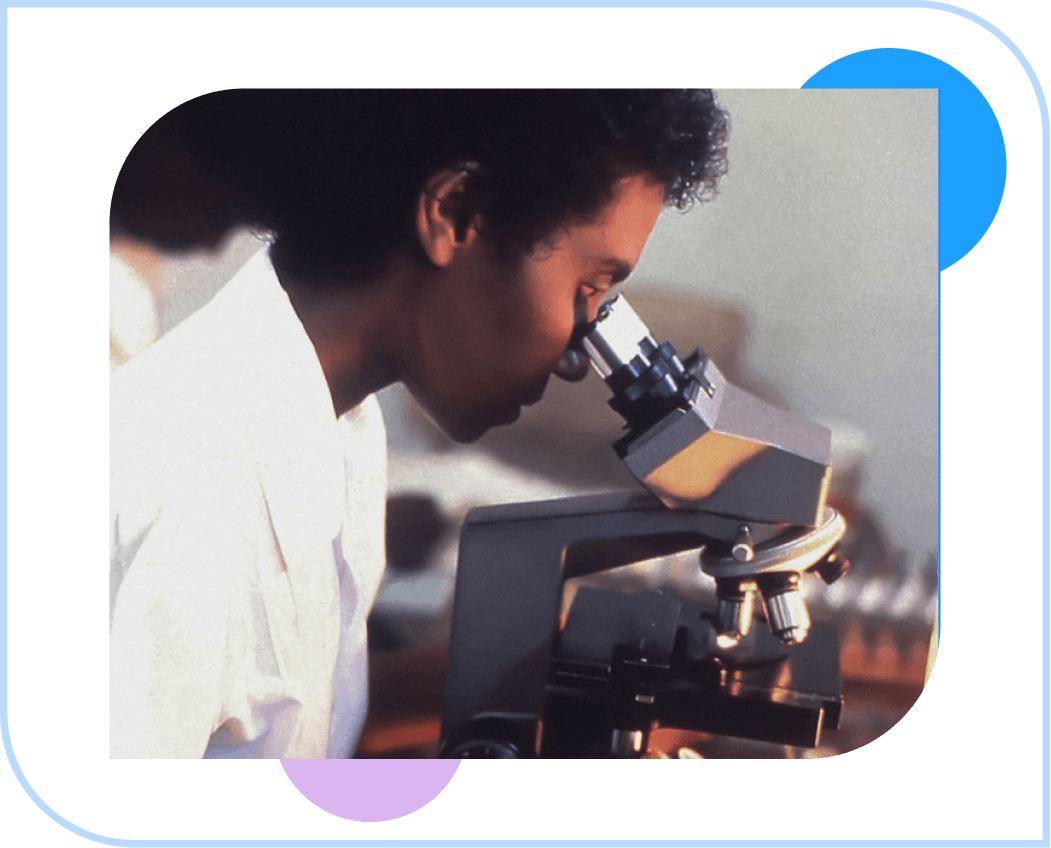 A man is looking through a microscope in a lab