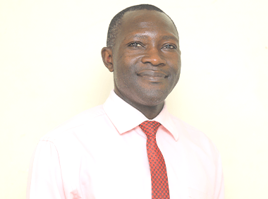 A man in a pink shirt and red tie smiles for the camera