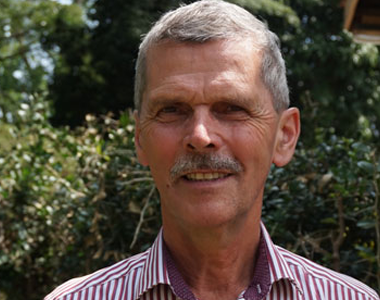 A man with a mustache is smiling for the camera while wearing a striped shirt.