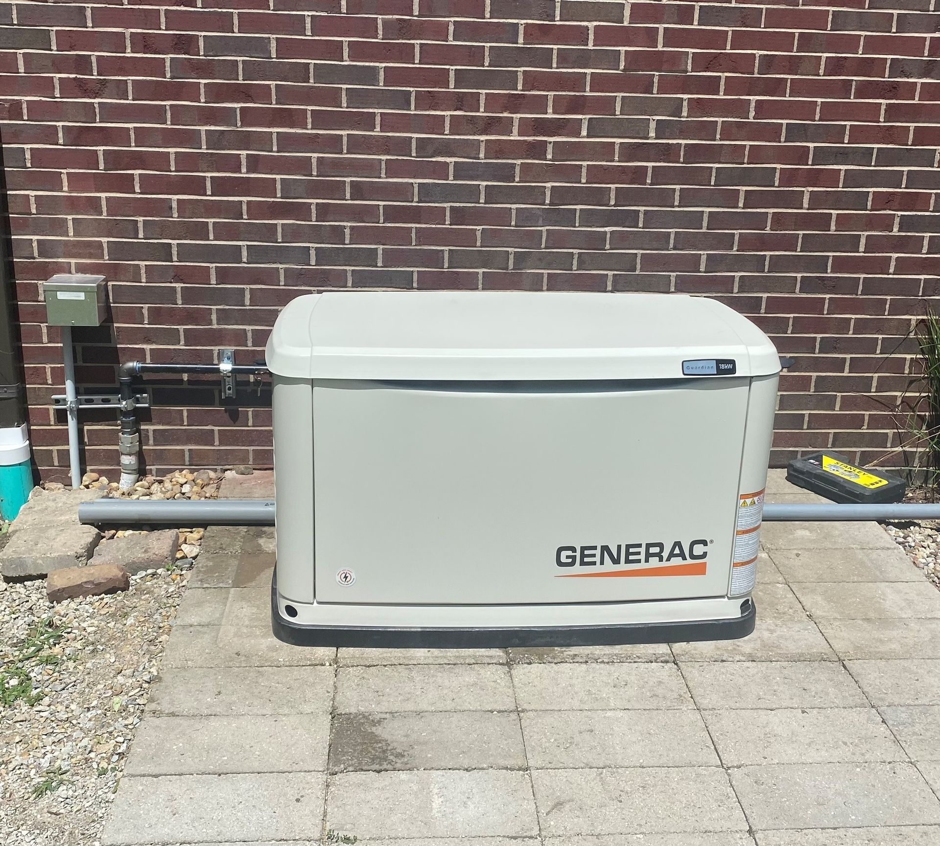 A generator is sitting in front of a brick wall