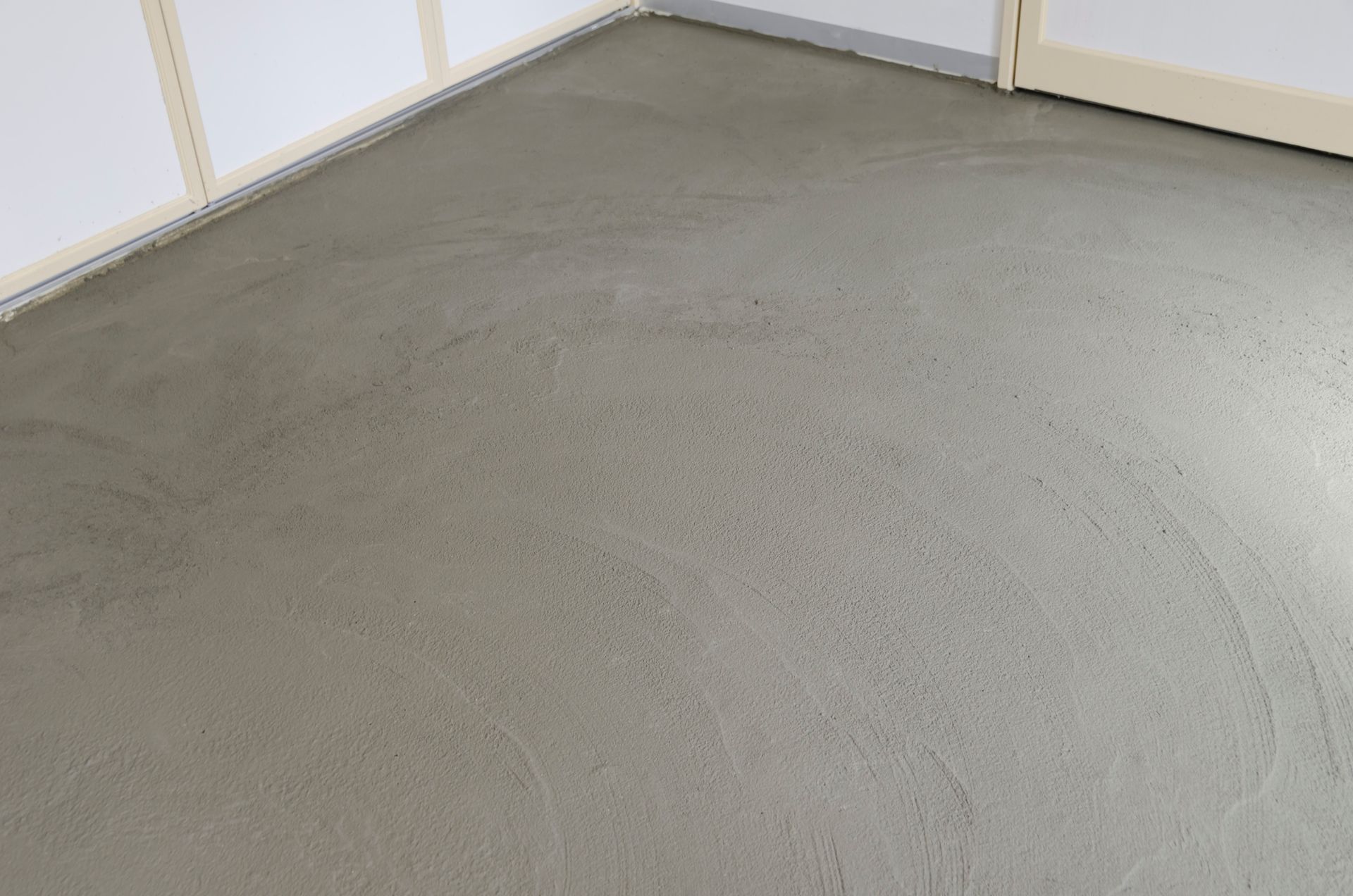 Angolo di stanza vuoto con moquette, pavimento grigio chiaro e pareti bianche