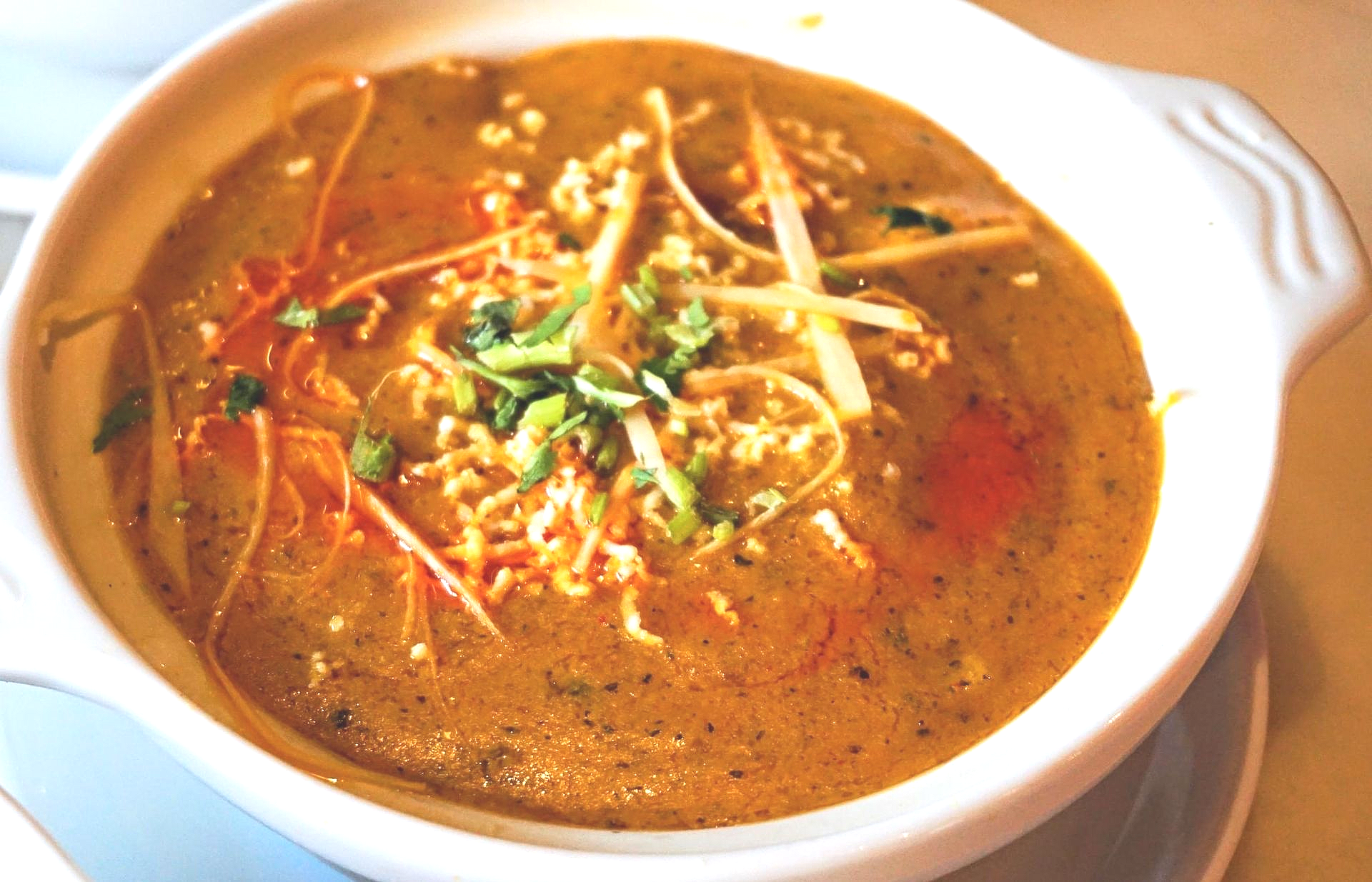 Bowl of creamy bowl of dal garnished with herbs, shredded vegetables