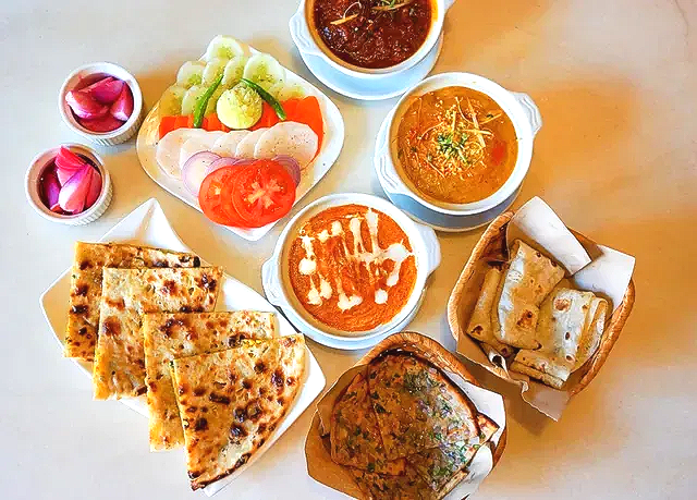 A spread of vegetarian dishes on the table — paneer curry, dal, bread from the tandoor, a tikka star