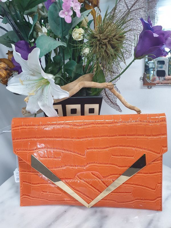 Orange Crocodile-textured Clutch With Gold Clasp, in Front of a Flower Arrangement — Shona's Lingerie in Hermit Park, QLD