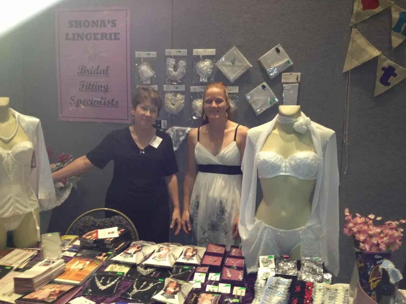 Two Women at a Lingerie Booth, Displaying Bridal Lingerie and Accessories — Shona's Lingerie in Hermit Park, QLD