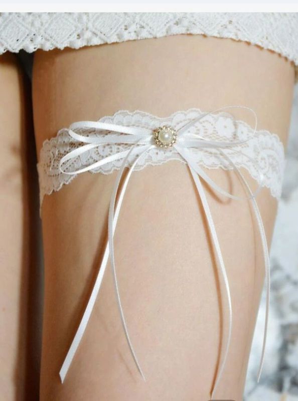 White lace garter with bow and pearl detail around a person's thigh. - Shona's Lingerie, Townsville, QLD.