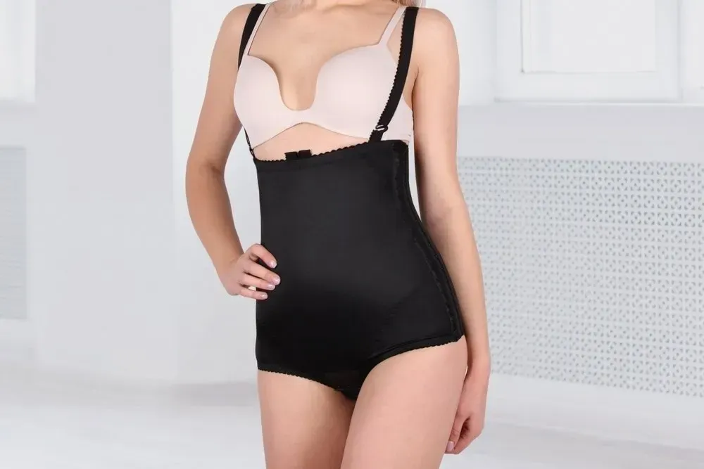 Woman wearing a black bodysuit with suspenders over a bra, standing indoors — Shona's Lingerie in Aitkenvale, QLD.