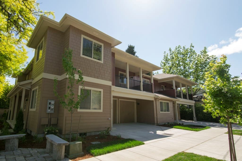 The exterior of a 2-story townhouse style unit, with beige siding and blue sky behind it