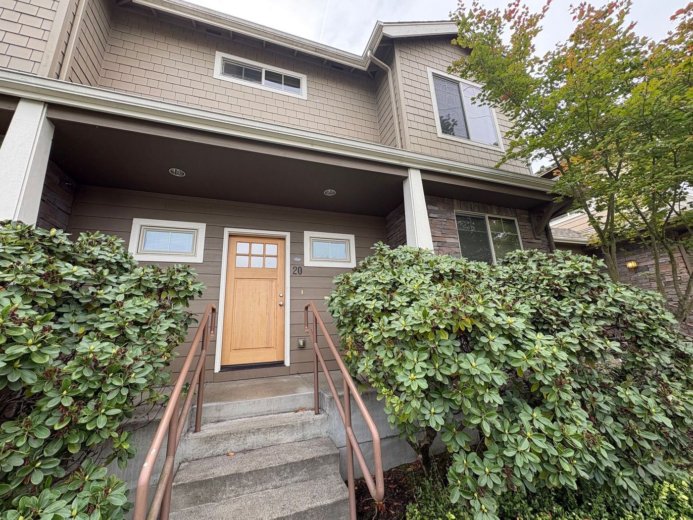 Exterior of a townhouse style apartment with wood front door and beige siding
