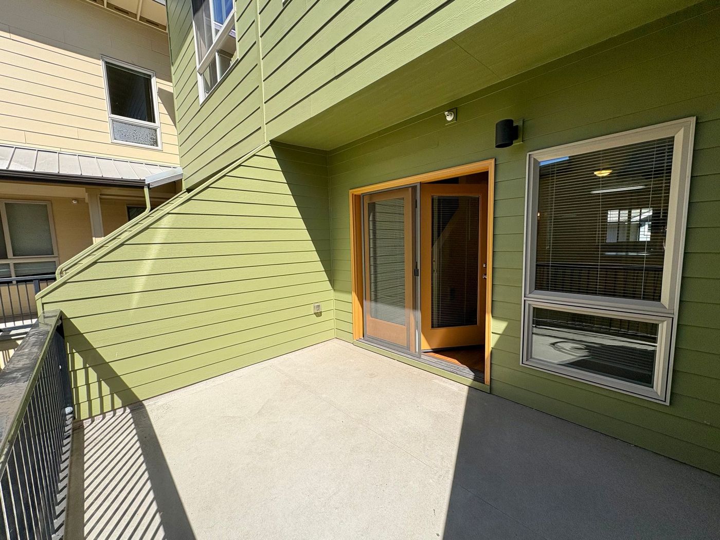 A large balcony with green siding and yellow french doors