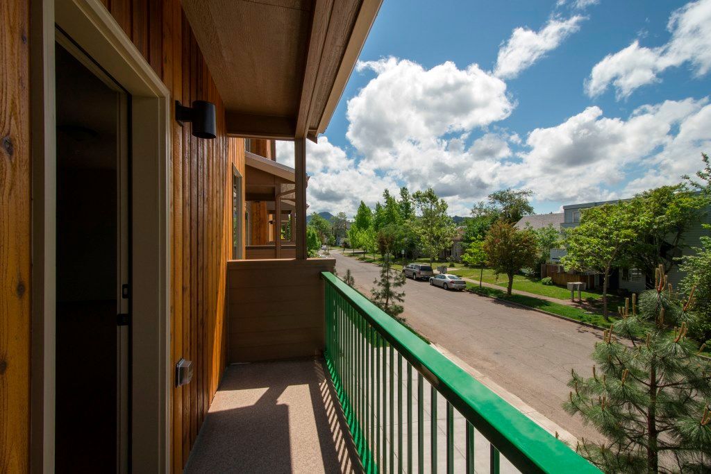 A balcony view of the street with blue sky and green spring trees