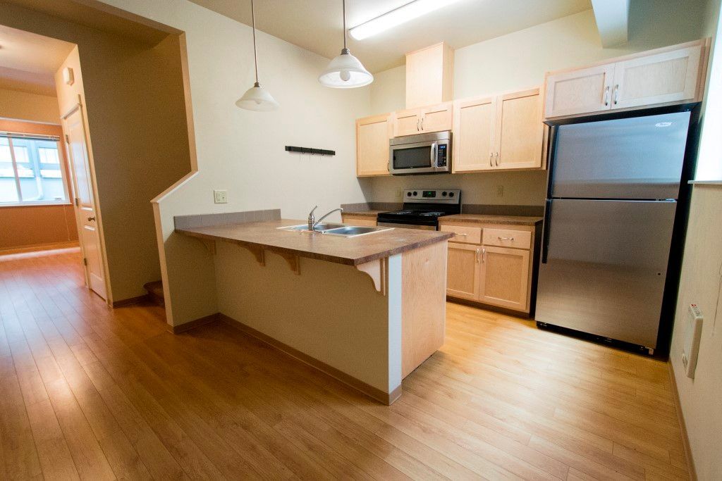 A kitchen with wood cabinets, stainless steel fridge, oven, and microwave, and an island