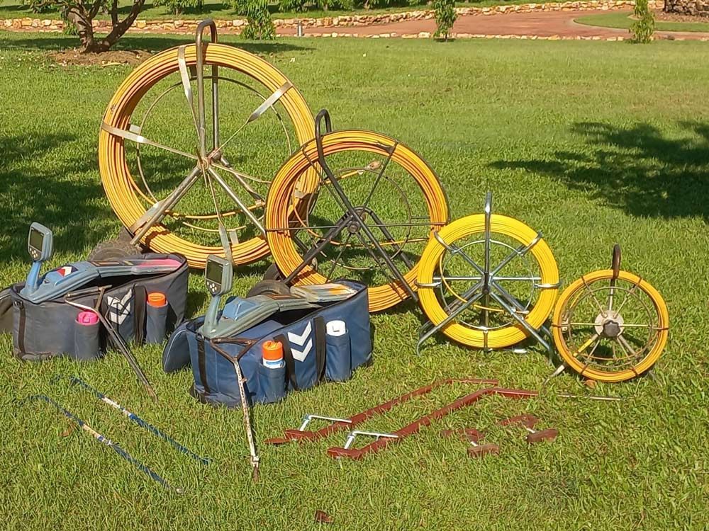 Yellow conduit reels, tools, and bags sit on green grass. — Austar Underground Services in Girraween, NT