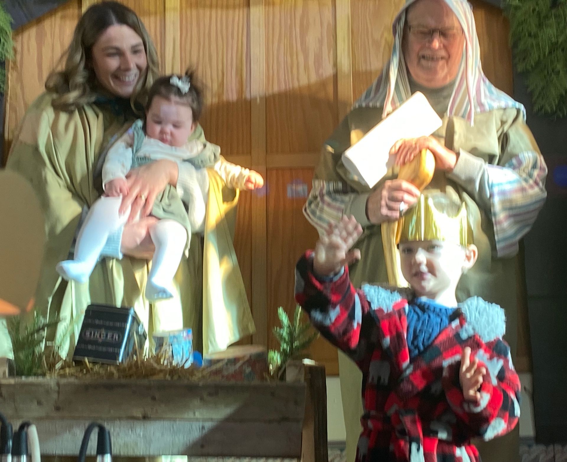 Two costumed people and two children posing indoors, one child holding up an award or gift