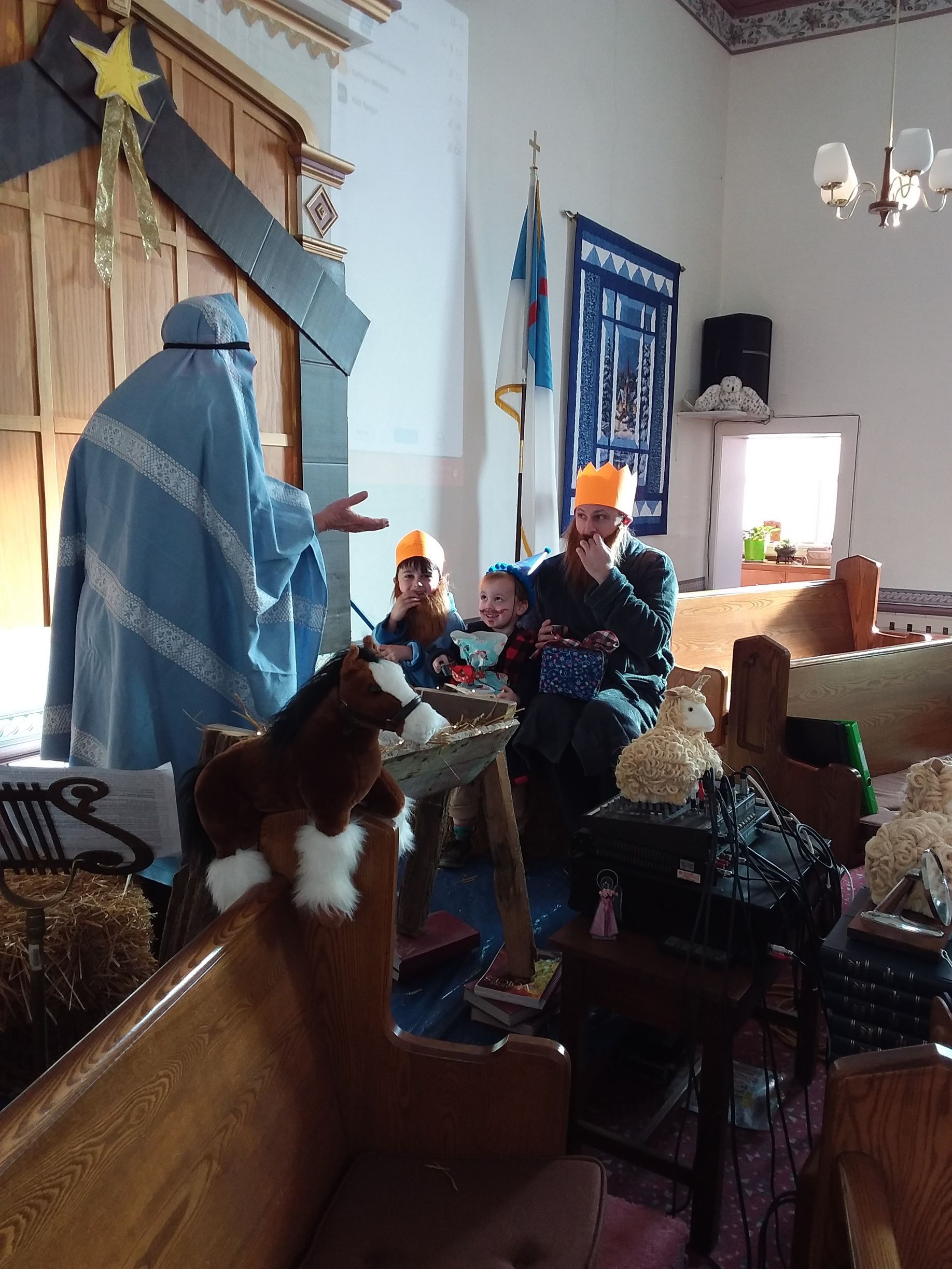 People seated in a decorated living room beside a large blue statue and star-shaped wall decor.