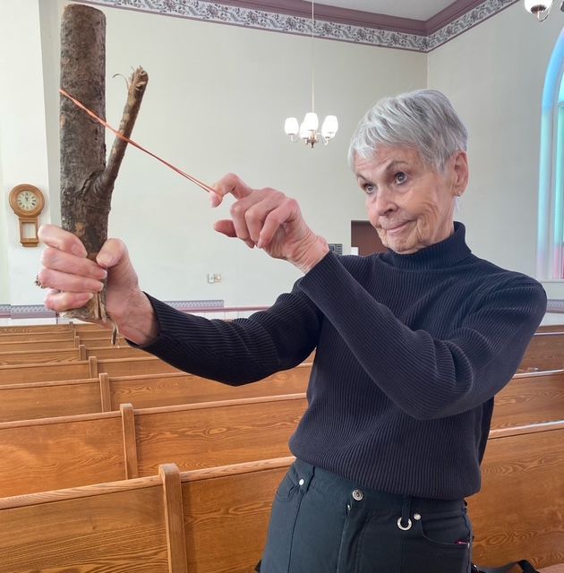 Woman using a slingshot indoors in a church pew area