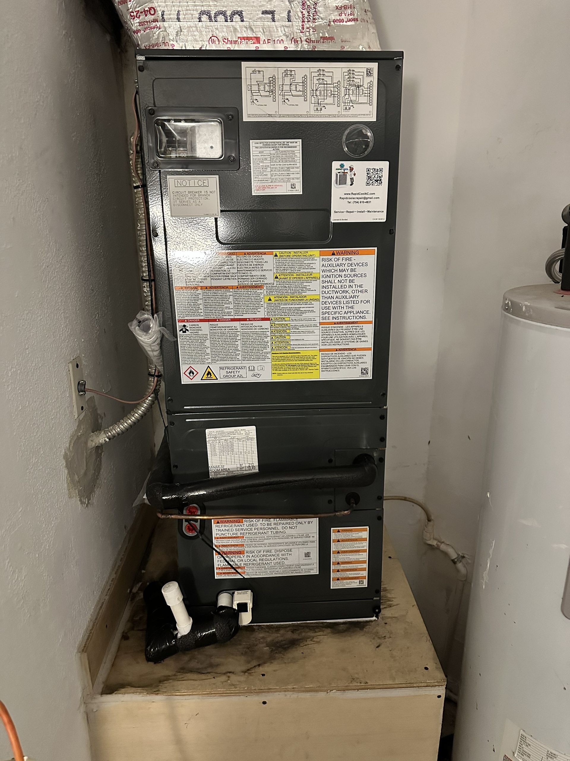Black HVAC/furnace unit in a narrow utility closet beside a water heater.