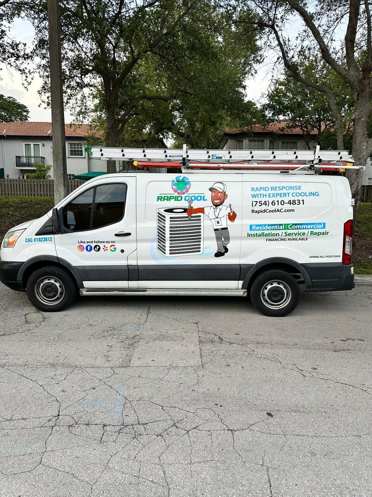 White service van with company branding parked on a street beside trees and houses.