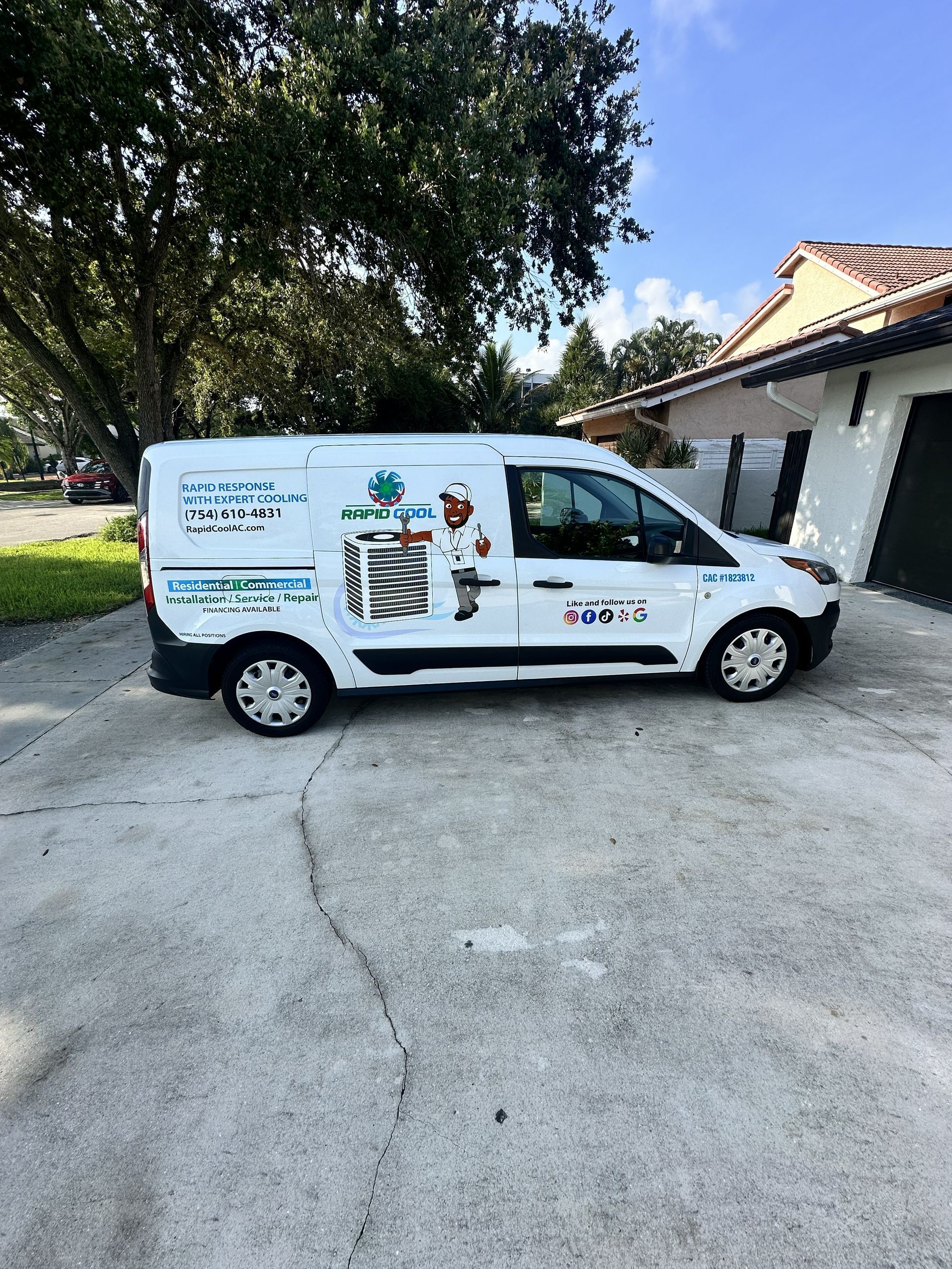 White service van parked on a driveway beside a house and trees, with company branding on the side.