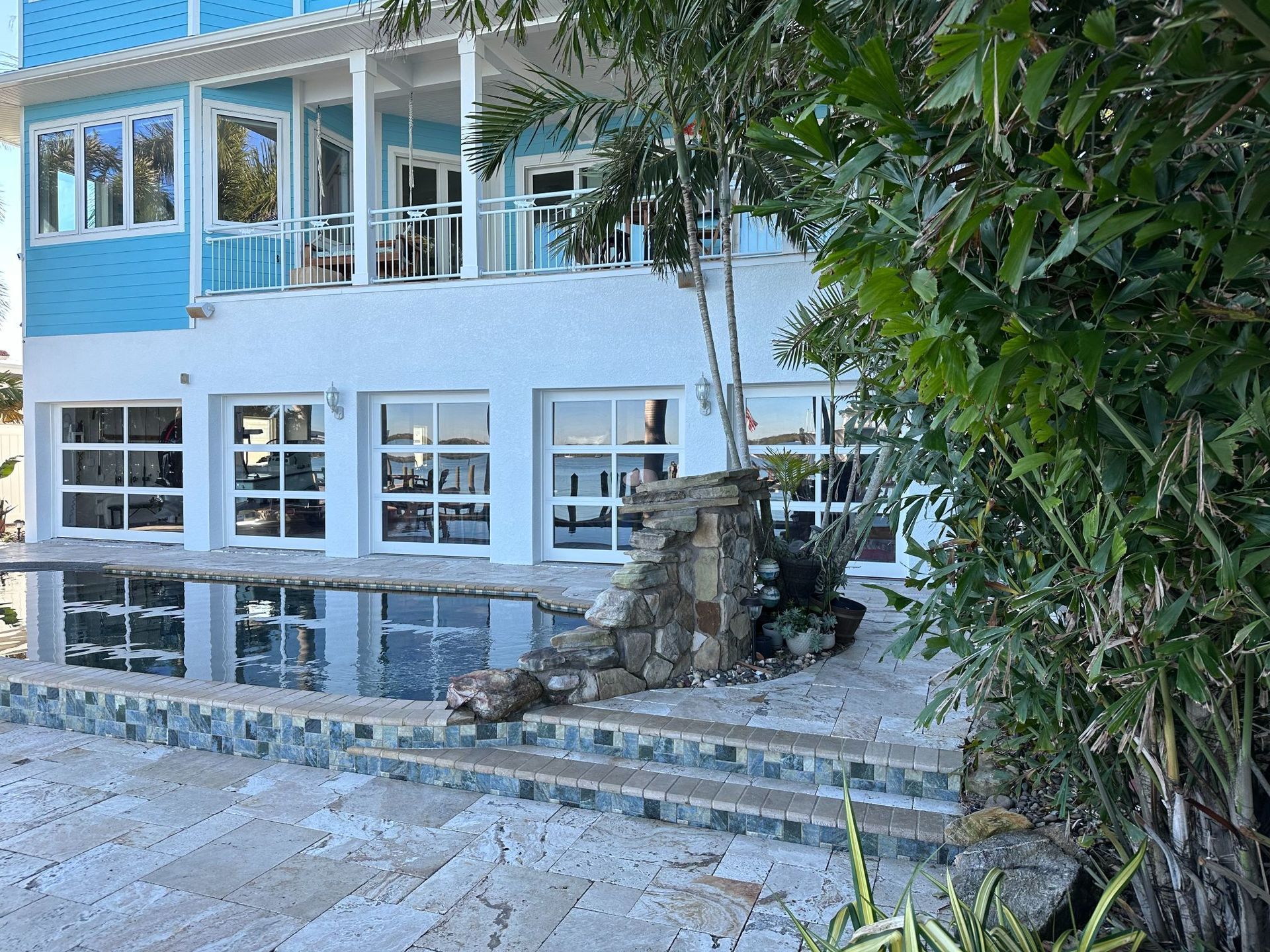 Blue and white beachfront house with a pool and steps leading up to it.