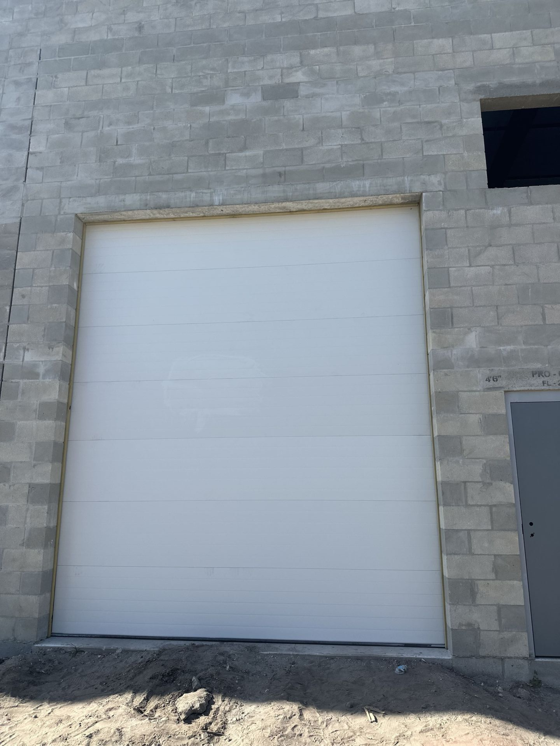 White garage door in a gray cinder block building.