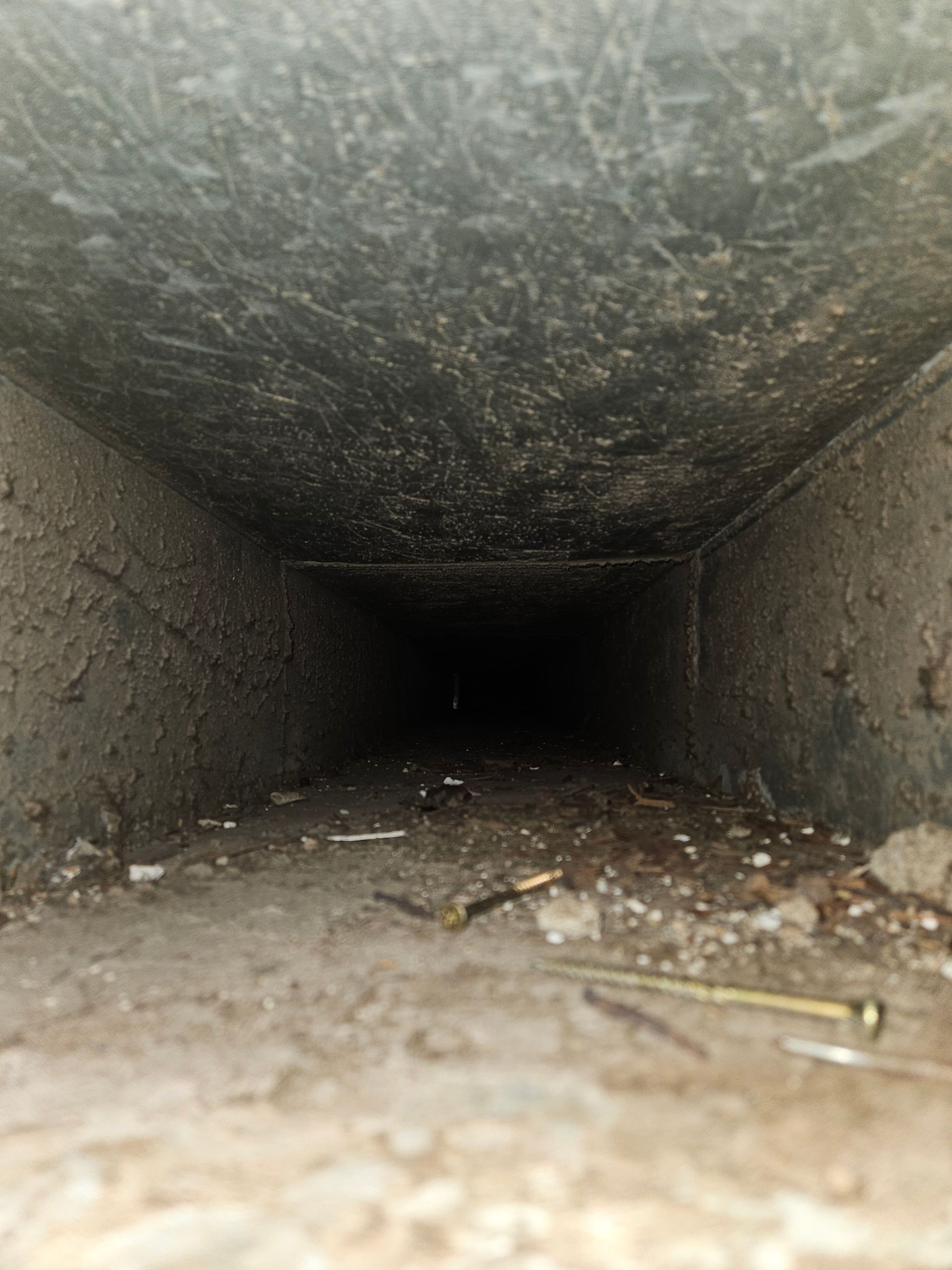 Interior view of a dirty air duct with dust, debris, and construction residue found in a Janesville, WI home
