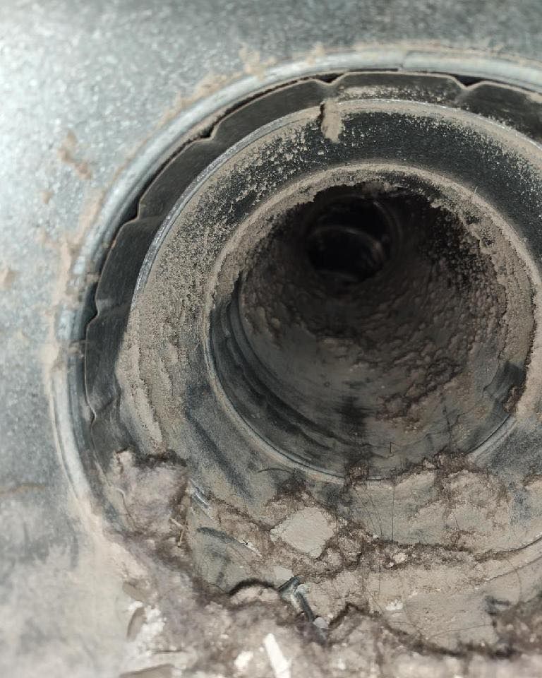 Close-up of a dusty, dirty vent opening in a metallic surface.
