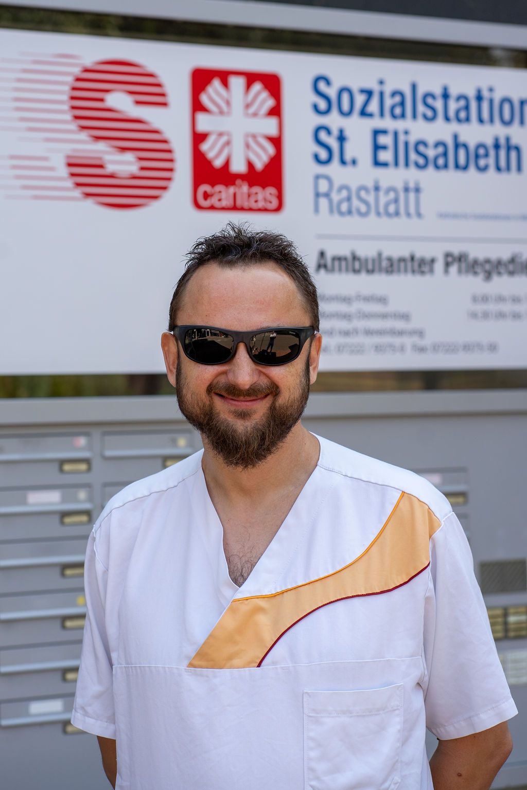 Pflegefachkraft vor dem Eingangsschild der Sozialstation Rastatt