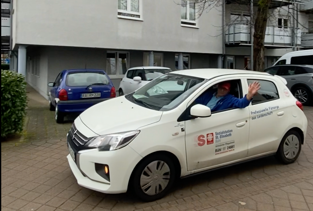 Mann lädt Box für Essen auf Rädern in Dienstwagen.