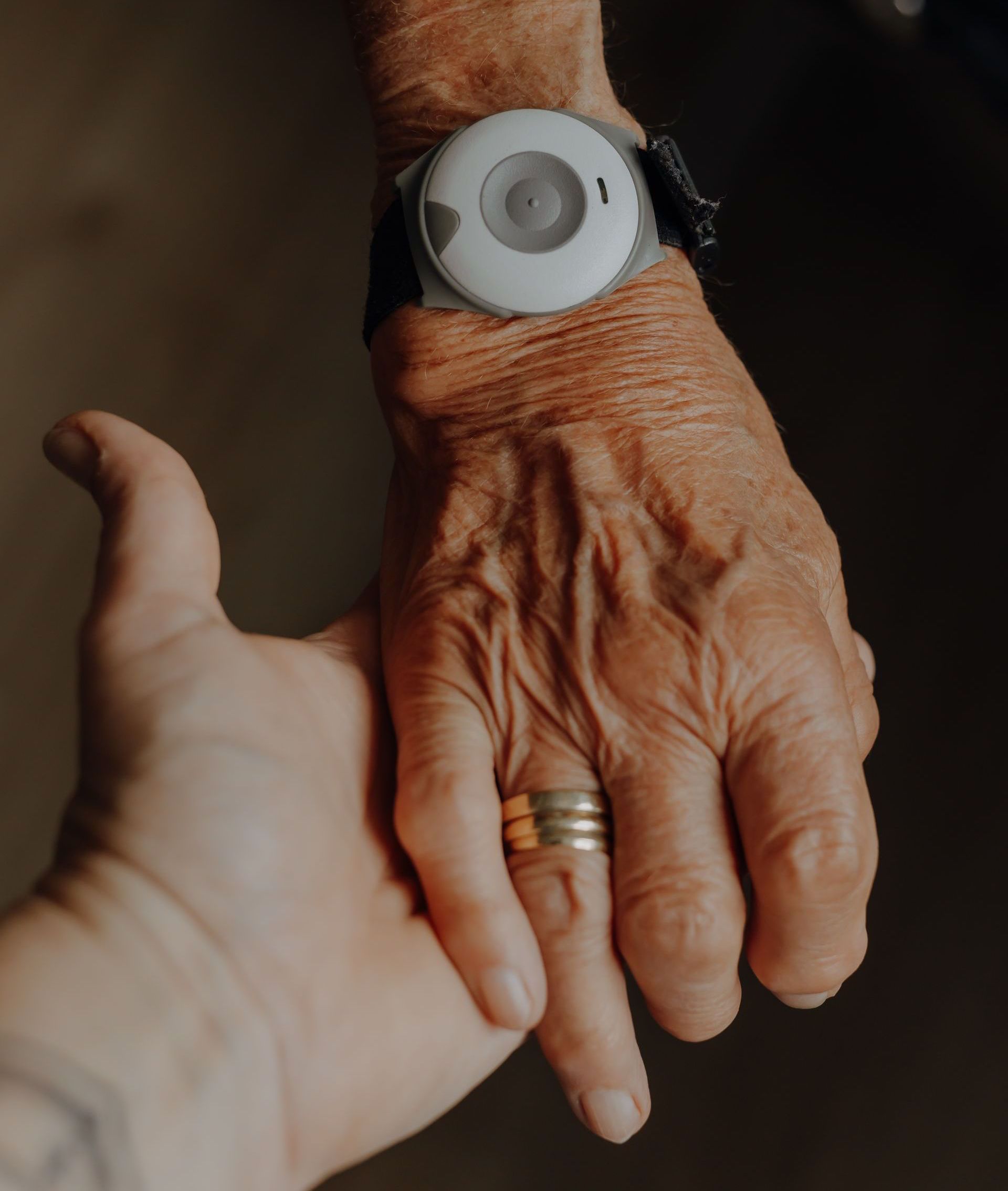 Arm einer alten Dame mit Hausnotruf-Knopf ums Handgelenk