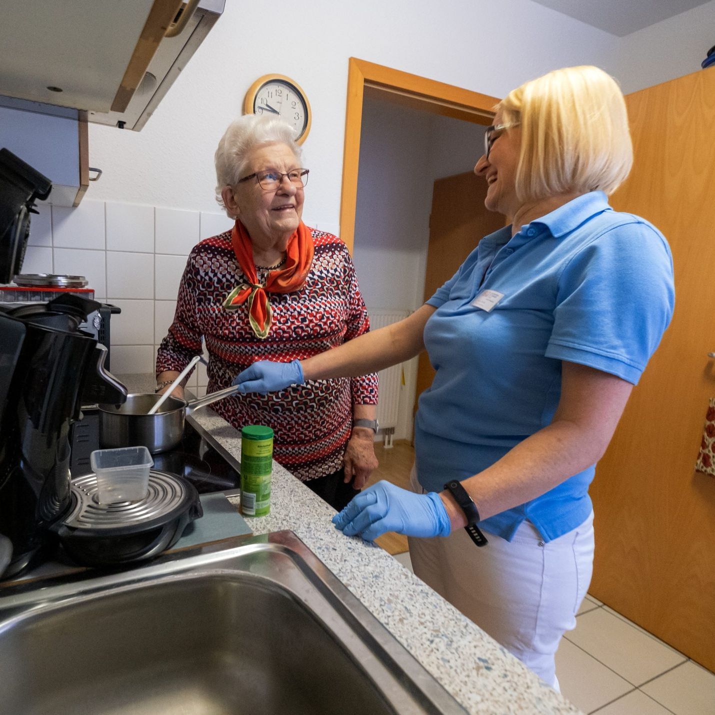 Hauswirtschaftskraft putzt Küche einer Seniorin.