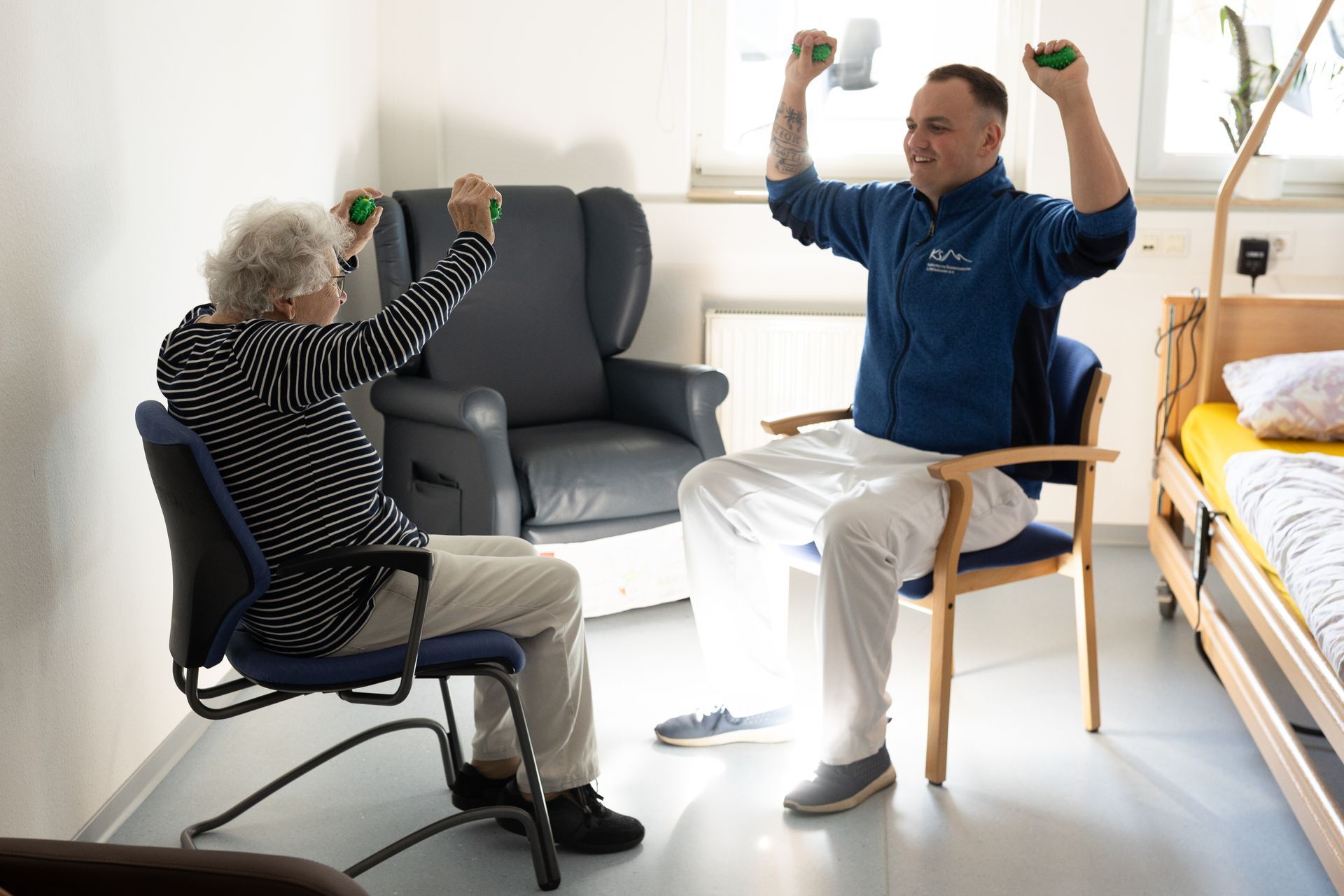 Zwei Gäste der Tagespflege machen Gymnastikübungen im Sitzen.