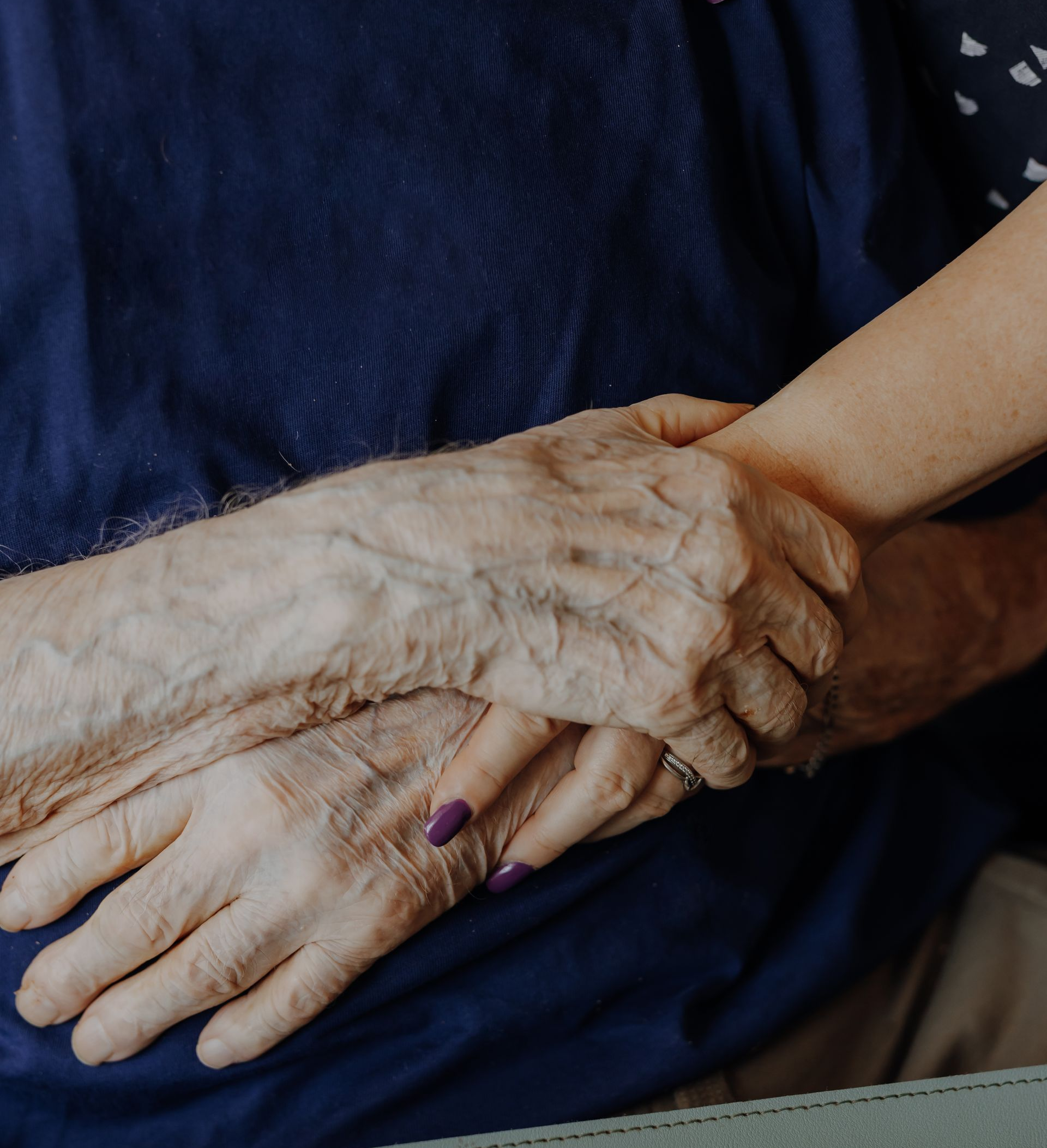 Arm eines alten Mannes Hand in Hand mit seiner Tocher, die ihn pflegt