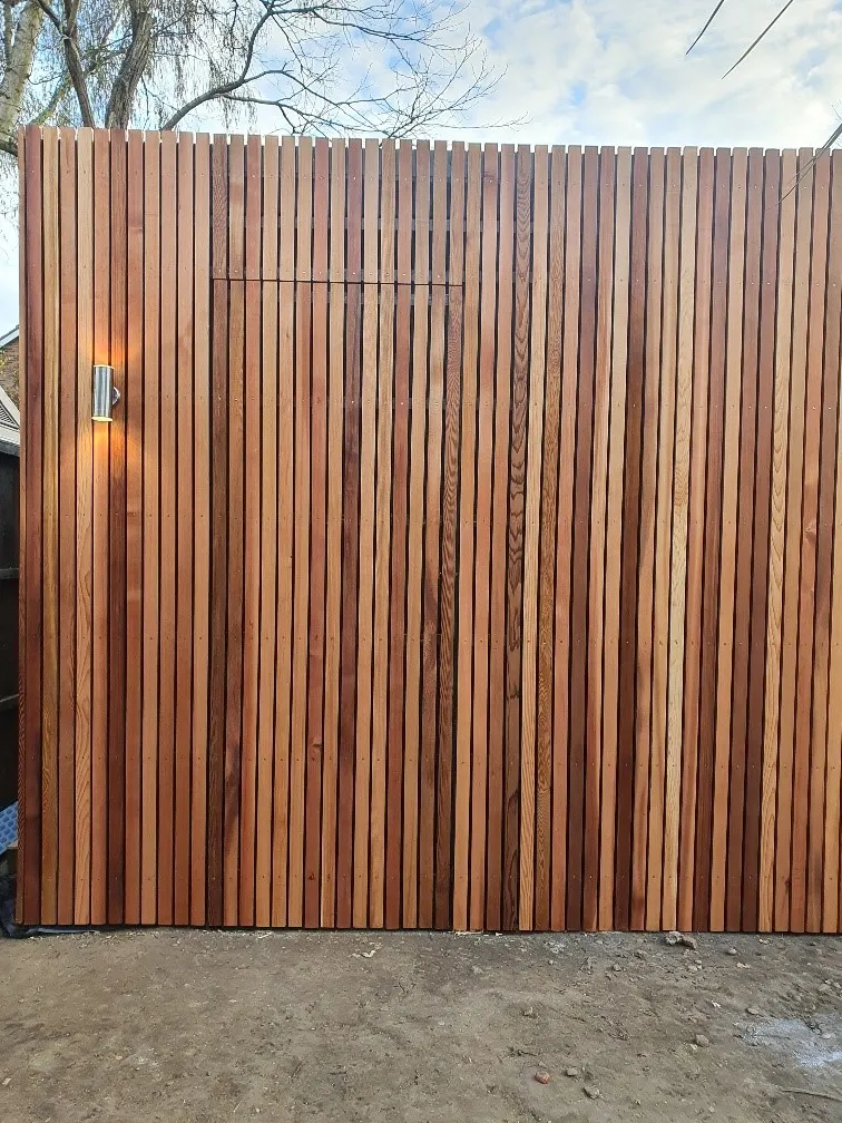 A large wooden fence with a door in the middle of it.