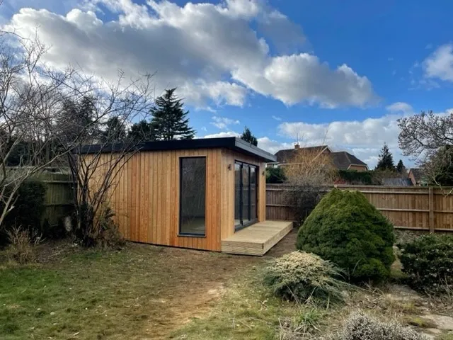 A Timber Garden Room is sitting in the middle of a backyard.
