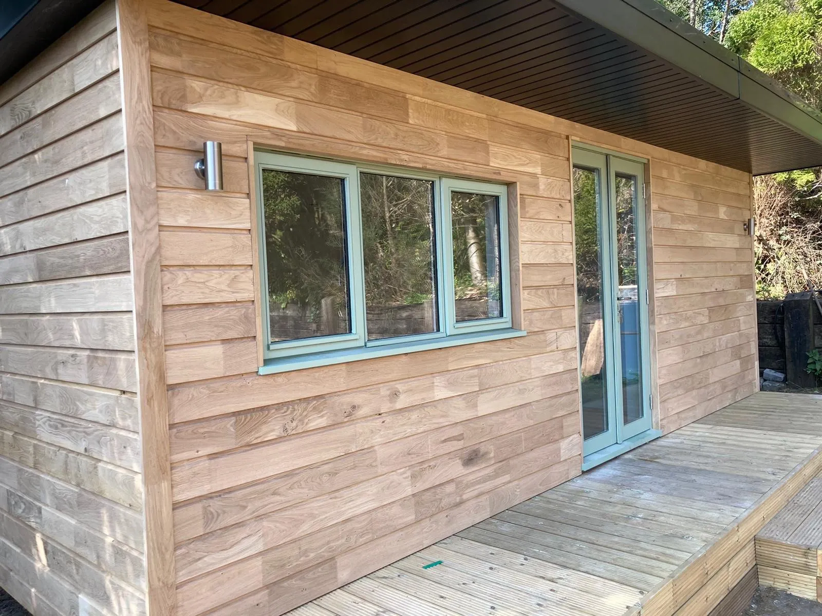 A Timber Garden Room with a wooden deck and a blue door.