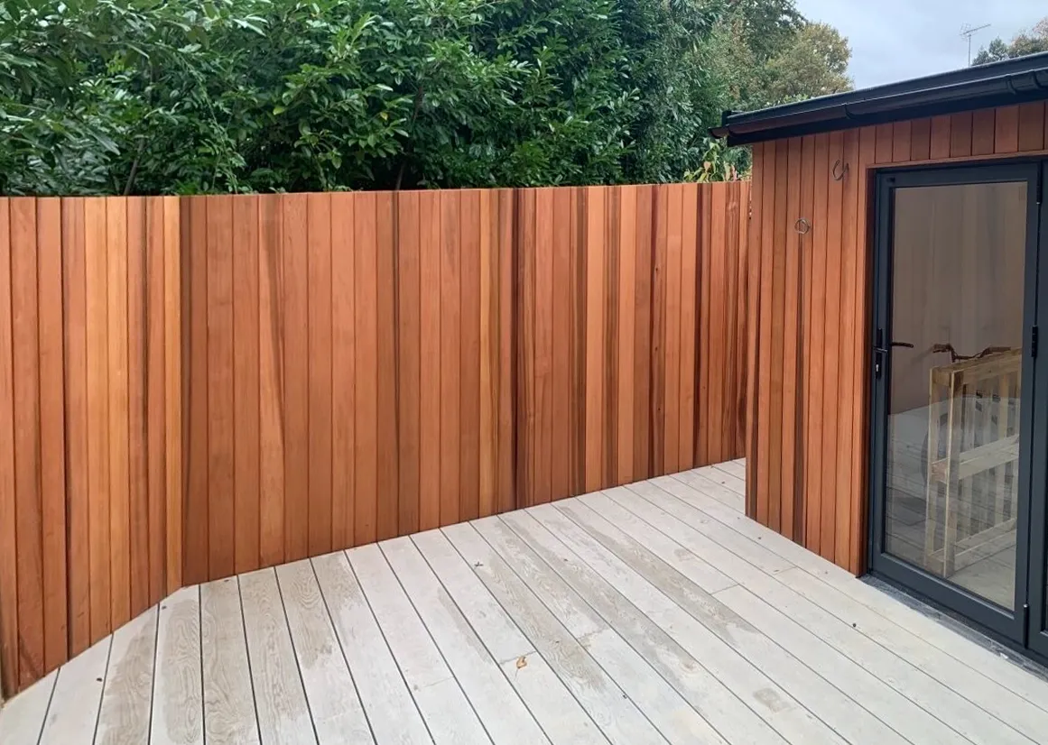 A wooden fence surrounds a deck with a sliding glass door.