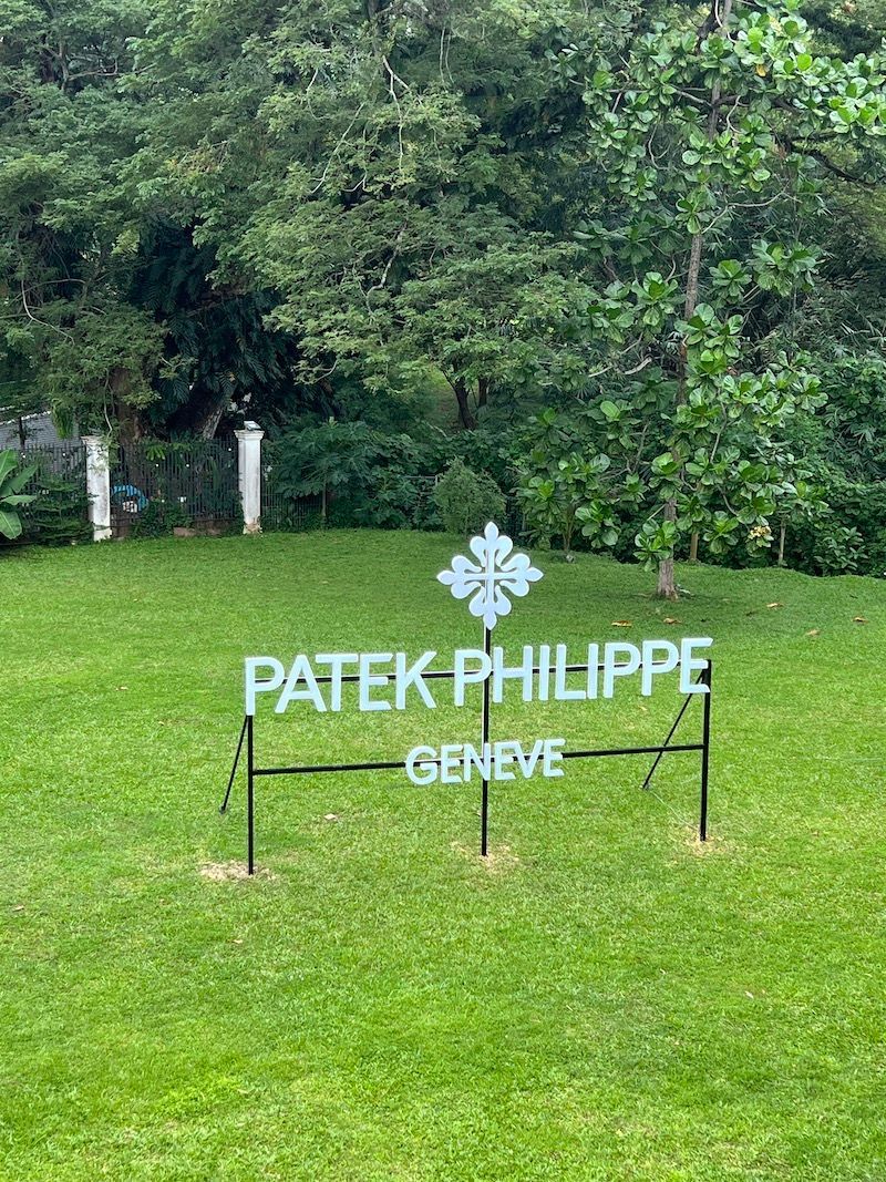 A patek philippe sign is sitting in the middle of a lush green field.