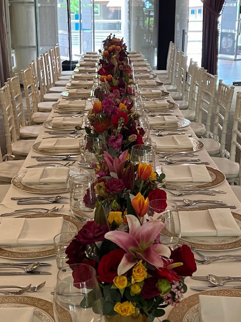 A long table with plates , glasses , and flowers on it.