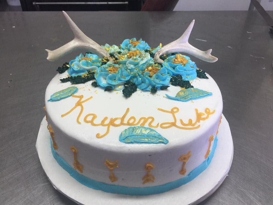 Cake decorated with blue and gold accents, antlers, and the name
